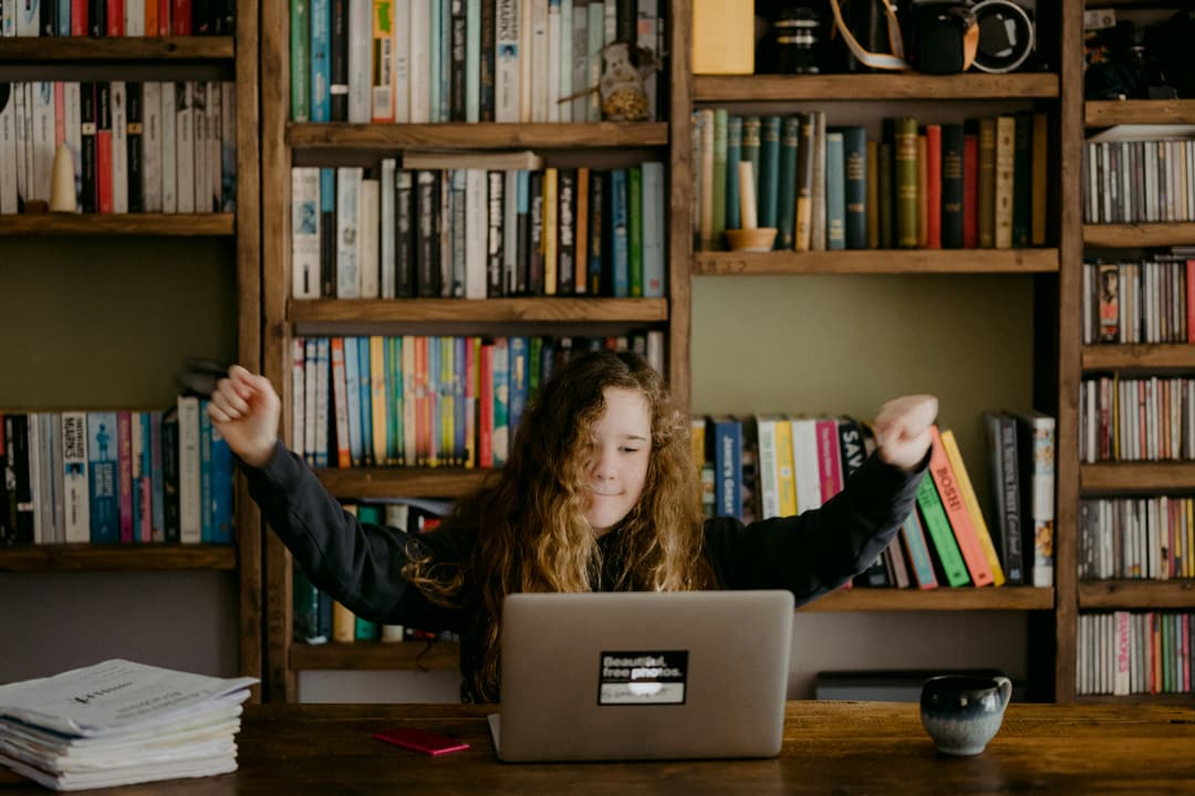 Unsplash image by Annie Spratt | A student siting in front of a laptop, excited about learning